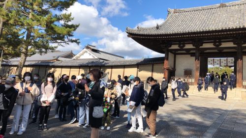 法隆寺のの前で見学の注意事項を聞いています。天気は晴れ、風が強いです。全員元気です。